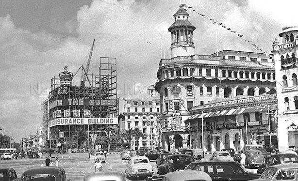 View of Ocean Building (right) and Asia Insurance Building (left) under construction at Collyer Quay, Singapore. Buildings were decorated to celebrate the coronation of Queen Elizabeth II.