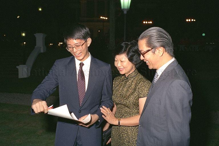 Patrick Tan Boon Ooi (left) showing his parents, Minister for Education Dr Tony Tan (right) and Mrs Mary Tan (centre), the President's Scholarship awarded him by President Wee Kim Wee during a reception at Istana.