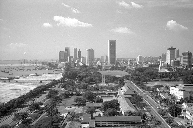 Bird's eye view of Beach Road in the direction of central business district at Shenton Way from Shaw Towers. From the foreground are Beach Road camp, followed by Singapore Armed Forces (SAF) Non-Commissioned Officers (NCO) Club, the Civilian War Memorial, the Padang and high-rise buildings in Shenton Way. On the left in the background are Anderson Bridge straddling Singapore River mouth, Fullerton Building and reclamation works in progress for the Marina area.