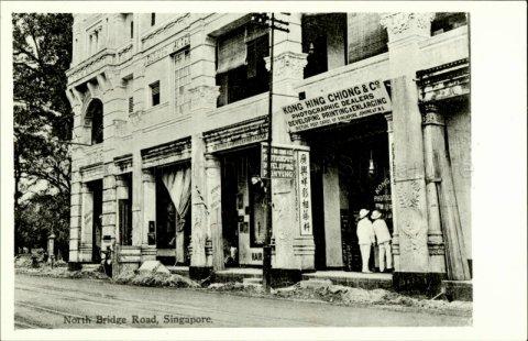 A corner of Adelphi Hotel at North Bridge Road, Singapore. Featured here is Kong Hing Chiong and Company, a photographic dealer offering picture postcards of Singapore, Johore and the Federated Malay States.