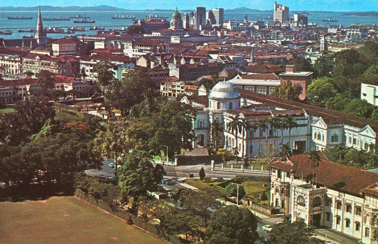Aerial view of Singapore between Fort Canning and Empress Place, looking towards the sea. Visible buildings include National Museum (centre, with dome, former Raffles Library and Museum) and St Andrew's Cathedral (left background, with spire).