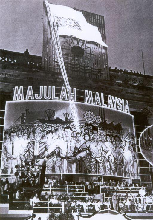 The Prime Minister of Singapore Lee Kuan Yew viewing march-past during parade marking Malaysia Solidarity Day at City Hall. Photo shows the poster of the Malaysian Multitude Marching Forward Hand-In-Hand with the words "Majulah Malaysia". The formation of Malaysia was officially proclaimed on 16 September 1963. PM Lee would lead in shouting "Merdeka" (Independence) three times to signify the independence of Singapore with the formation of Malaysia.