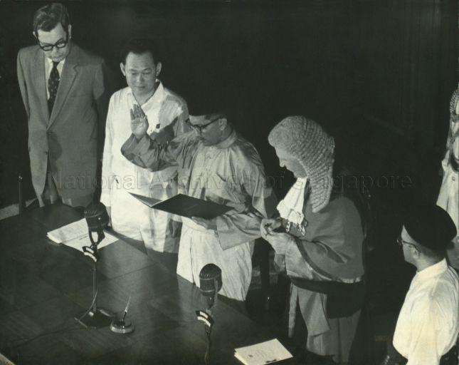 Yusof Ishak being sworn in as Yang Di-Pertuan Negara by Chief Justice Sir Alan Rose at Installation Ceremony, with Prime Minister Lee Kuan Yew (2nd from left) looking on