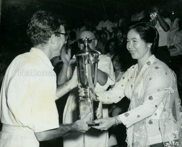 Puan Noor Aishah presenting gold trophy to Ian Barnwell, winner of Singapore's first Grand Prix