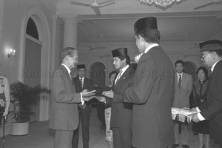 Presentation of State awards between Sultan Hassanal Bolkiah of Brunei and President Wee Kim Wee at Istana during the Sultan's first state visit to Singapore. Looking on are Minister for Trade and Industry and Second Minister for Defence (Services) Brigadier-General Lee Hsien Loong (third from right) and wife Madam Ho Ching.