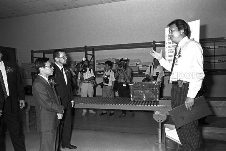 DHL Air Express Centre official briefing Minister for Communications and Minister of State for Trade and Industry Mah Bow Tan (left) during his tour of DHL Air Express Centre at Tai Seng Drive during its opening. The Minister is accompanied by co-founder of DHL Larry Hillblom (second from left).