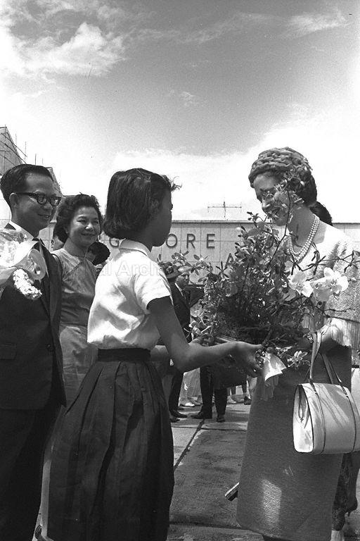 Lim Siew Yong of Whampoa Government Secondary School presenting bouquet of flowers to Queen Fabiola of Belgium at Paya Lebar Airport during the send-off. Looking on are Deputy Prime Minister Dr Toh Chin Chye and Mrs Toh.