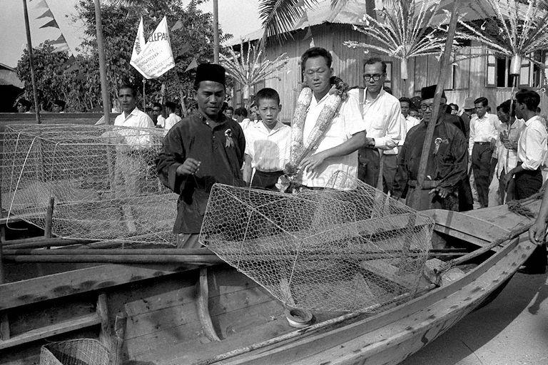 Prime Minister Lee Kuan Yew and his son, Lee Hsien Loong, viewing fishing boats and nets at Pulau Sekijang Pelepah during their tour of the Southern Islands. With them are Penghulu of the island Tok Khairen (right) and Bai Kassan.