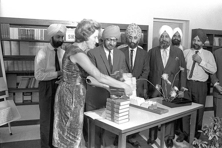 President of Sri Guru Nanak Sat Sangh Sabha Mr Inder Singh Bajaj presenting books donated by the Sikh community to Director of National Library Miss A Priscilla Taylor at adult lending department of the library. Among those present are textile magnate Sardul Singh Narula (with white turban; second from right) of Indersons Co and renowned businessman Ranjit Singh Dang (right).