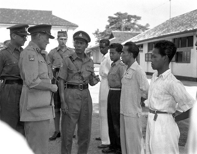 General Officer Commanding Singapore Base District Major-General A G O-Carroll Scott (second from left), talking to new recruits during annual inspection of Singapore Volunteer Corps. In the centre is Lieutenant Jan bin Mustaffa, MBE, who acted as Malay interpreter. On the extreme left is Captain J E Gabain.