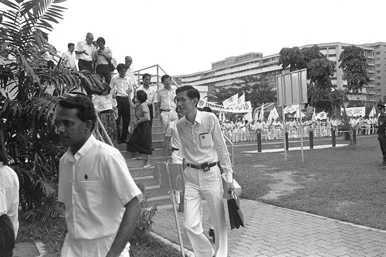 General Election 1988 - Candidates leaving Yishun Secondary School, the nomination centre for Sembawang Group Representation Constituency (GRC) and single member constituencies of Nee Soon Central, Nee Soon South and Thomson, on nomination day. In the foreground are People's Action Party (PAP) candidates K Shanmugam [Sembawang Group Representation Constituency (GRC)] and Dr Koh Lip Lin (Nee Soon South). At the staircase with reporters are United People's Front (UPF) candidate for Sembawang GRC Harbana Singh (top) and Singapore Democratic Party (SDP)'s candidate for Nee Soon South Yong Chu Leong.