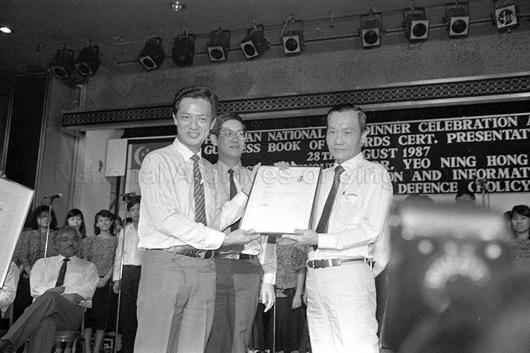 Minister for Communications and Information and Second Minister for Defence (Policy) Dr Yeo Ning Hong (left) showing the Guinness Book of Records certificate he received on behalf of the Oriental Singers. At the Marina Square Christmas Cheer '86, the Oriental Singers sang for 74 hours and five minutes setting a world record. Looking on is Member of Parliament for Fengshan Dr Arthur Beng (centre), who is also hosting the Fengshan National Day dinner at Mandarin Hotel.