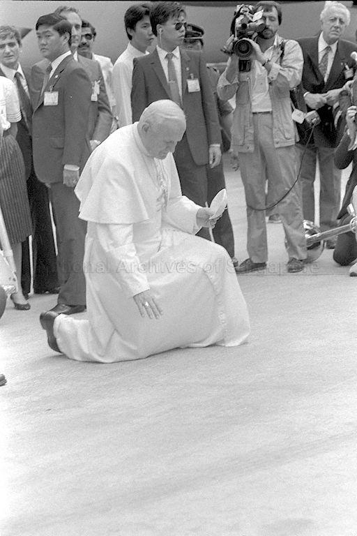 His Holiness Pope John Paul II kneeling to kiss the Changi Airport tarmac, his traditional gesture marking the start of a state visit, upon arrival in Singapore
