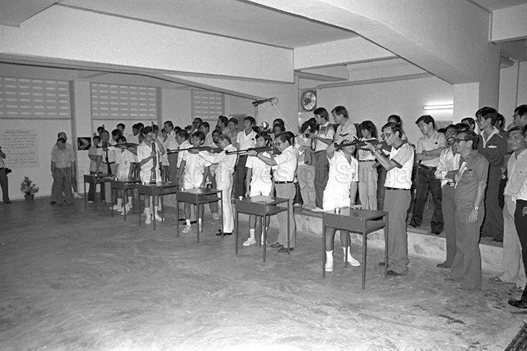 Members of Hua Yi School's air rifle club giving instructions to (from right) Members of Parliament Lau Peng Sum (Yio Chu Kang) and Rohan Kamis (Telok Blangah), Trade and Industry Minister Dr Tony Tan, Minister of State for Labour as well as Chairman of National Productivity Board Dr Wong Kwei Cheong, Senior Parliamentary Secretary to Prime Minister's Office and also Member of Parliament for Tiong Bahru Ch'ng Jit Koon (hidden), and Parliamentary Secretary to Ministry of Trade and Industry and Social Affairs Sidek Saniff (hidden).