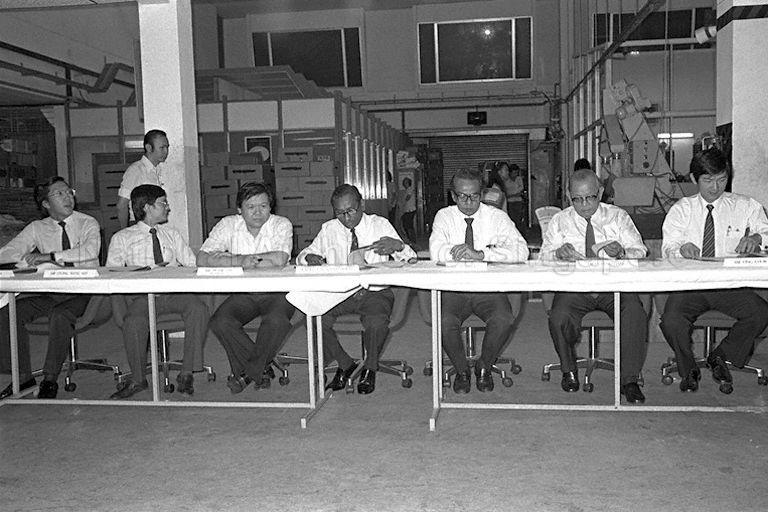 The Sixth Annual Assay Commission meeting at the Singapore Mint to receive the samples of coins randomly set aside from coins produced for the annual assay or test (to be done by Singapore Institute of Standards and Industrial Research and chemical analysis of gold coins by the Singapore Assay Office). Members of the Commission are (from left) General Manager of Branches and International Banking Division of United Overseas Bank Limited Ernest Wong Yuen Weng (first); Deputy General Manager of Board of Commissioners of Currency of Singapore Leong Weng Kee (second); Chairman of the Commission Justice T S Sinnathuray (fourth); Director of Department of Scientific Services of Ministry of Health M C Dutt (fifth); Founding member of Ee Peng Liang & Company and President of Singapore Council of Social Service Dr Ee Peng Liang (sixth); and Director of Materials and Electrotechnology Division of Singapore Institute of Standards and Industrial Research (SISIR) Ong Chor Eong (seventh). Third from left is General Manager of Singapore Mint Peter Tay.
