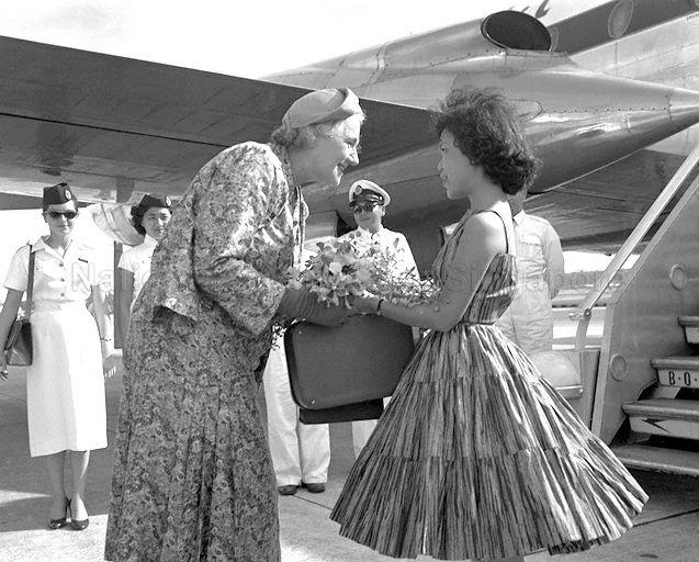 Lady Dorothy Macmillan, wife of British Prime Minister, receiving a bouquet of orchids from Iris Lim, 14-year-old daughter of Chief Minister Lim Yew Hock, before boarding her plane for London.