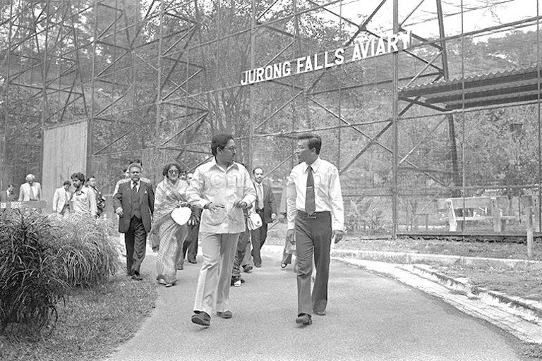 King Birendra of Nepal, accompanied by Queen Aishwarya (hidden) and his sister, Princess Sharada Shah is briefed during a walking tour of Jurong Bird Park. The royal couple and their entourages are on a five-nation tour of Sri Lanka, Singapore, Burma, Bangladesh and India.