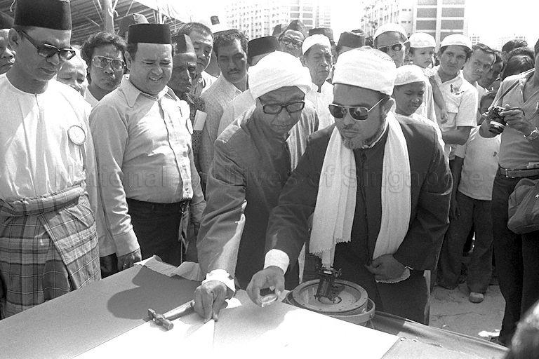 Isa Syed Mufti Syed Isa Semait (foreground, right) using a compass to