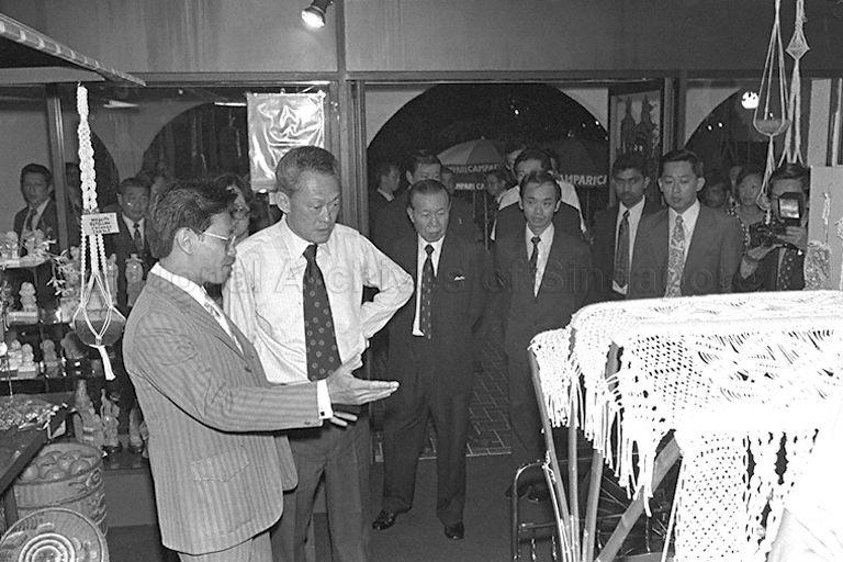 Prime Minister Lee Kuan Yew at a handicraft shop during his tour of the $5 million Singapore Handicraft Centre in Tanglin at its official opening. To his left is Chairman of Singapore Tourist Promotion Board Runme Shaw.