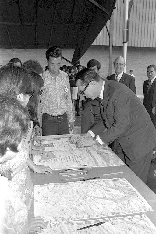 Minister for Finance Hon Sui Sen autographing on banners upon his arrival for opening ceremony of Philips Machine Factory and Telecommunications Factory in Jurong. Looking on in the background from right are former Chairman of the Economic Development Board Tang I-Fang and Vice-President of N V Philips Gloeilampenfabrieken of Holland D Noordhof.