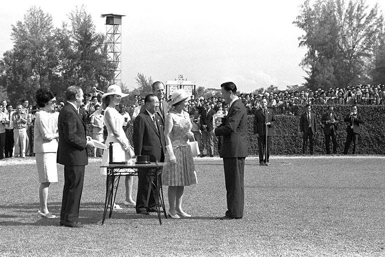 Queen Elizabeth II presenting challenge trophy of the Queen Elizabeth II Cup to owner of winning horse, Singaporean lawyer Lee Ah Seong, at Singapore Turf Club in Bukit Timah. Looking on are (from right to left) Duke of Edinburgh Prince Philip, club chairman Tan Sri Runme Shaw, Princess Anne, club secretary D R H Brown and Mrs Shaw. 