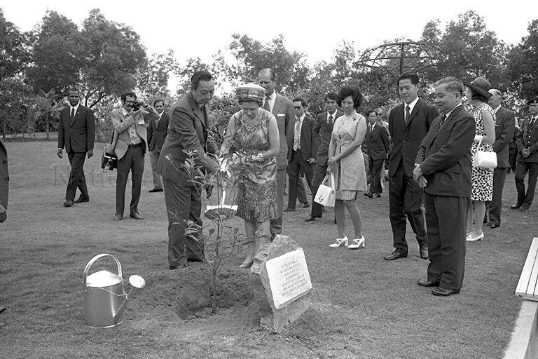 Queen Elizabeth II, assisted by Chairman of Jurong Town Corporation (JTC) Woon Wah Siang, planting a tembusu tree at Jurong Hill Park as Duke of Edinburgh Prince Philip, Minister for Culture Jek Yeun Thong (second from right) and other officials look on