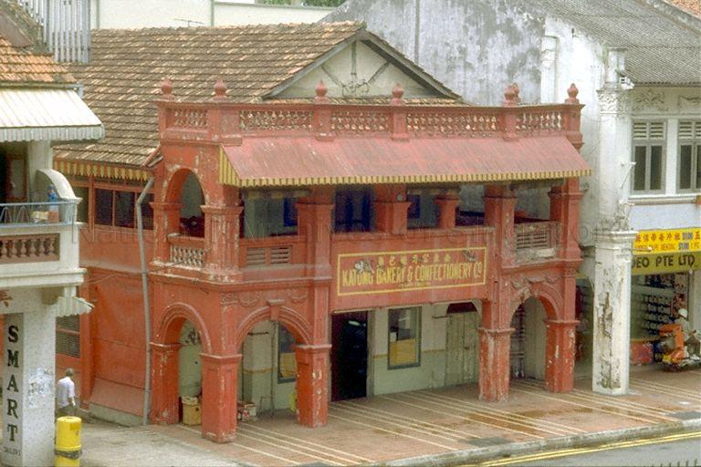 Although it was more popularly referred to as the "Red House Bakery", its actual name is Katong Bakery & Confectionery Company. Probably the name "Katong Bakery" is more appropriate and fondly remembered by Katongnites because there is also a red coloured building and a confectionery called "Red House" at the corner of Bras Basah Road and Victoria Street. Katong Bakery is housed in a row of old shop-houses along East Coast Road. The gap to the right of the bakery leads to another famous shopping Katong landmark called "Tay Buan Guan Supermarket".