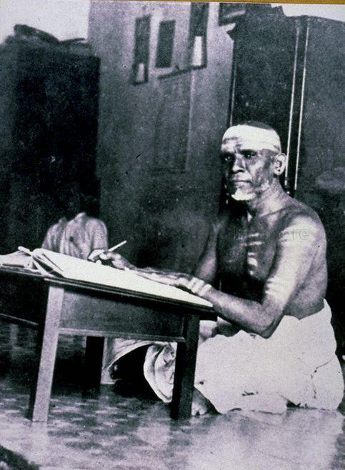 Photograph of a Chettiar with his low wooden table, most likely a money lender. The chettiar – who specialised in business loans – is seated in his kittangi (office). Such offices were located at and around Market Street.