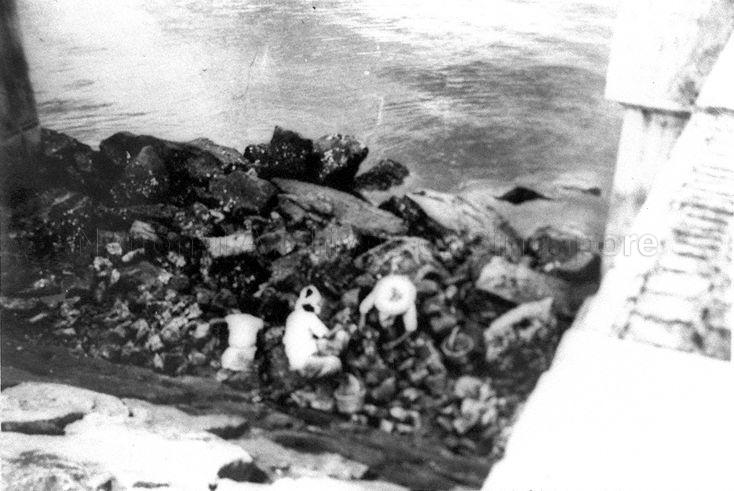 Picking up debris at part of blown-up Causeway that links Singapore to Johore Bahru in Malaya