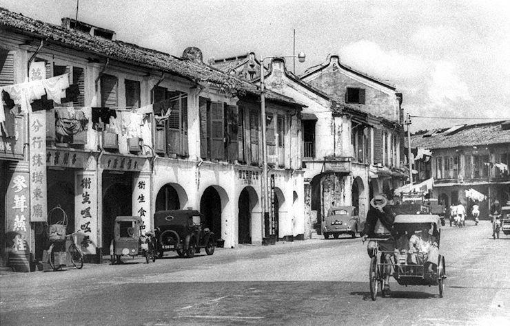 Main street in Chinatown, Singapore, with shophouses on both sides. Modes of transport include the trishaw which was introduced in April 1914. With the subsequent rising popularity of motor-cars, trishaws were relegated to providing cheap transport for short distances and for carrying goods from the wet market.