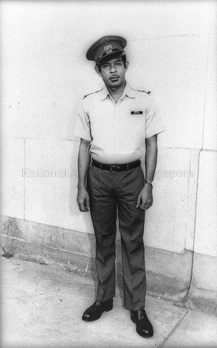 Postman posing for photograph in uniform. The "GPO" on his hat stands for General Post Office.