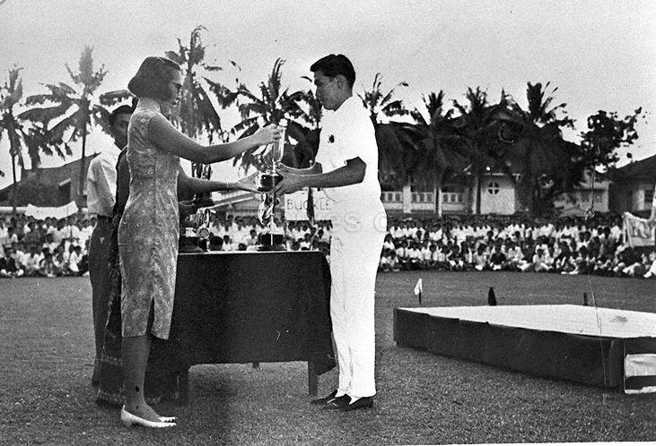 Mrs Lee Kuan Yew presenting trophy to overall champion William Phua (Class 1) during Sports Day at Raffles Institution. William won firsts in 100 yards sprint, 220 yards sprint, long jump, triple jump and javelin.