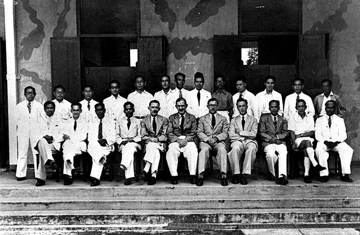 Group photograph of staff of Raffles Institution: (front row, left to right) Sinnathamby, C A Peterson, T E K Retnam, K M R Menon, R F Bomford, F L Shaw (Principal), Ogle, J Le Prevost, Ting Siew Choon, H N Balhetchet, V Ambiavagar; (back row, left to right) Abdul Rahim Aziz, Yapp Thean Chye, Chua Leong Hean, Tan Teck Chwee, Wee Seong Kang, Low Kee Pow, Tan Kim Yong, Ismail Aziz, Vaithinathan, Thong Sing Ching, Seow Cheng Joon, Boey Cheng Kee, R K Sharma