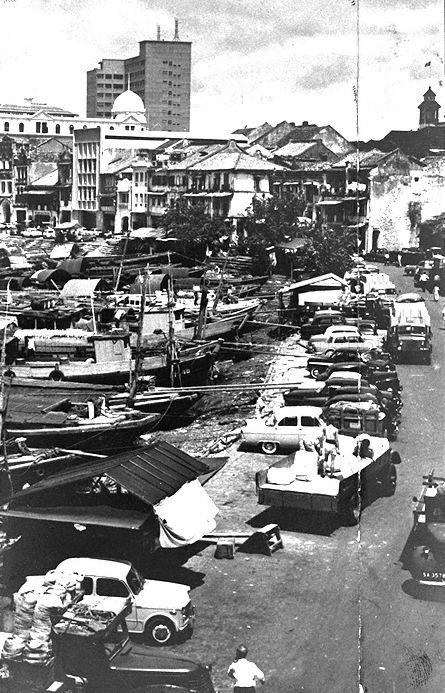 View of motor vehicles and twakows or lighters along bank Singapore River at Boat Quay