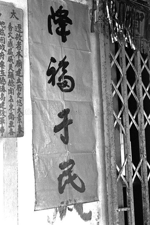 Pulau Tekong -- Calligraphic banner at Chinese temple with the words (from top down) "jiang fu yu min" meaning blessings be upon the people. Next to it is note (partially visible) informing of relocation of temple under resettlement programme for the island.
