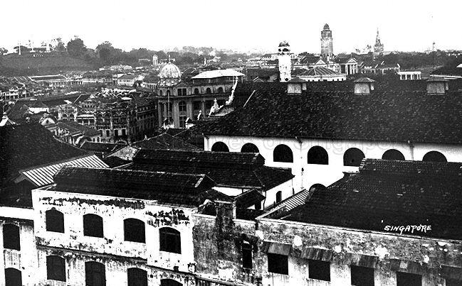 Aerial view of Singapore near Raffles Place. The tower of Guthrie and Company's head office building and the clock tower at Victoria Memorial Hall are visible.