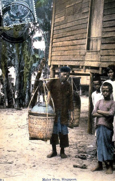 Malay "kueh" or cakes hawker carrying his wares and Malay boys in a "kampong" or village, Singapore