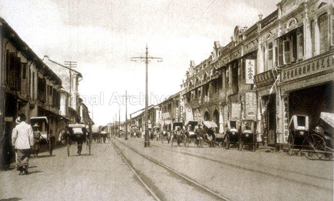 View of North Bridge Road with rickshaws lining the street, Singapore. North Bridge Road view from Arab Street Junction toward Blanco Court and Royal Theatre.