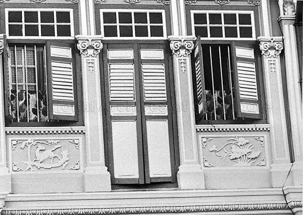 Shophouse No. 6 Koon Seng Road bought by a Hindu family, Gangabai. Classical Ionic columns with timber door and window frames, adapted to Singapore's tropical climate through use of louvres for ventilation. Vertical iron bars spanning the length of windows provide added security.