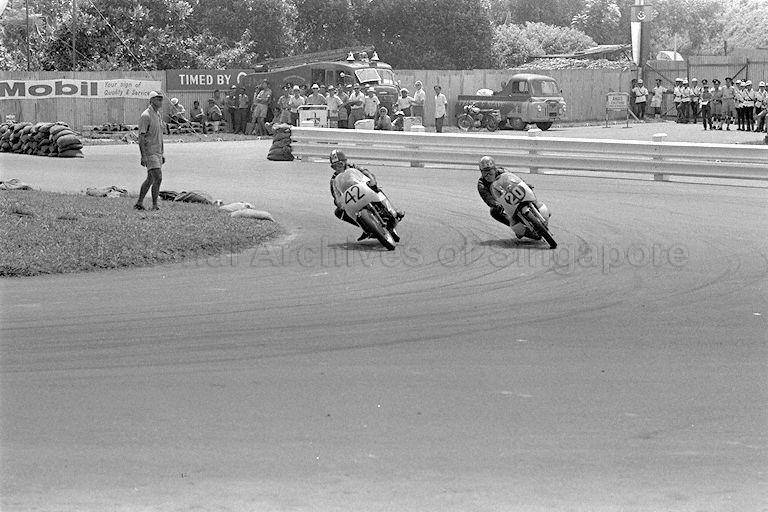 Hiroshi Hasegawa on his Yamaha passing rider on Aermacchi at Sembawang hairpin during Singapore Grand Prix 1966