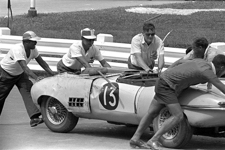 Course marshalls and officials pushing the Jaguar "E" with registration JC 13 out of the racecourse after it overturned during Grand Prix 1966. The driver from Johore, F A Johns, died on the spot.