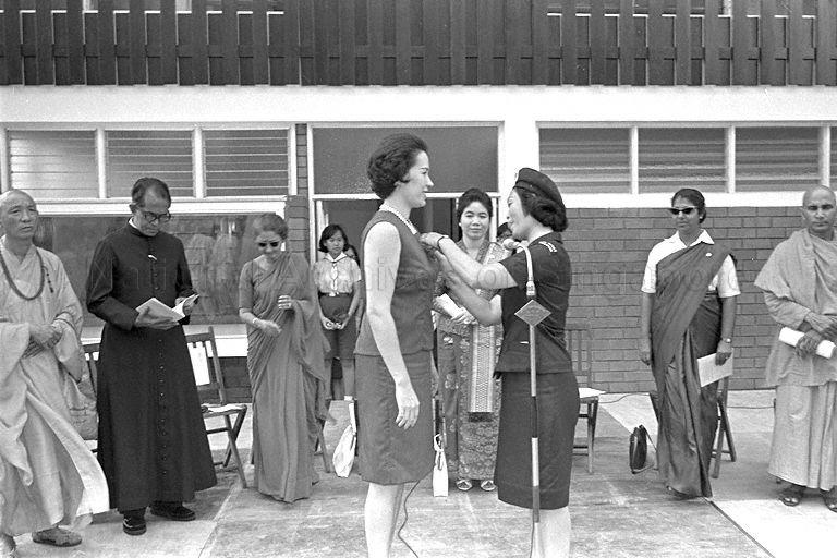 Acting Chief Commissioner of Girl Guides Madam Wong Ho Heng (right) presenting guide badge to President of Girl Guides Association Mrs Wee Chong Jin at opening of the Girl Guides Association Headquarters at Clemenceau Avenue. Looking on is First Lady Puan Noor Aishah.