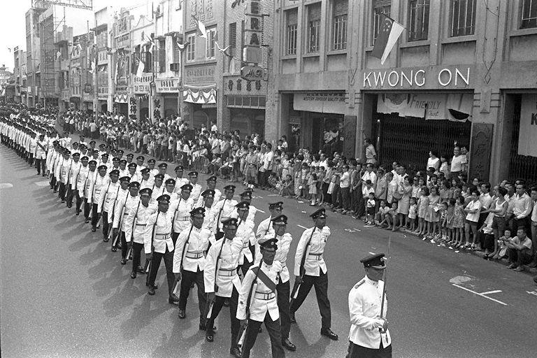 National Day Parade 1966 at the Padang - Guard of Honour contingent from the Singapore Infantry Regiment marching past delighted spectators lined along the roadsides in Chinatown