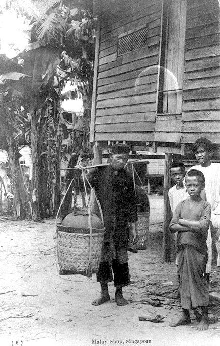 Malay "kueh" or cakes hawker carrying his wares and Malay boys in a "kampong" or village, Singapore