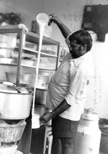 An Indian man preparing "teh tarik", a traditional beverage prepared by "pulling" the mixture of tea and condensed milk through the air