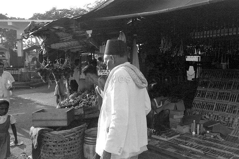 The man in the foreground is wearing a tarboosh (or fez), a red felt hat with a tassel attached to the top, that was popular during time of the Ottoman empire in the 19th and early 20th centuries. It was then worn by Christian, Jew and Muslim men alike. It continued to be worn by older Muslim men even after the fall of the empire.