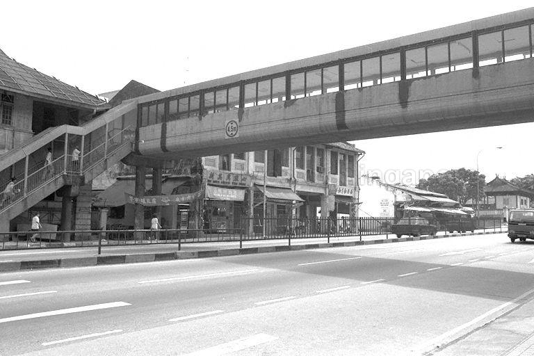 Shophouses along Upper Serangoon Road, to the right of the junction of Upper Serangoon Road and Yio Chu Kang Road. The camera is facing away from the City. These shophouses and the overhead bridge were demolished for the widening of Upper Serangoon Road and the construction of Serangoon Viaduct, which opened in 2002.