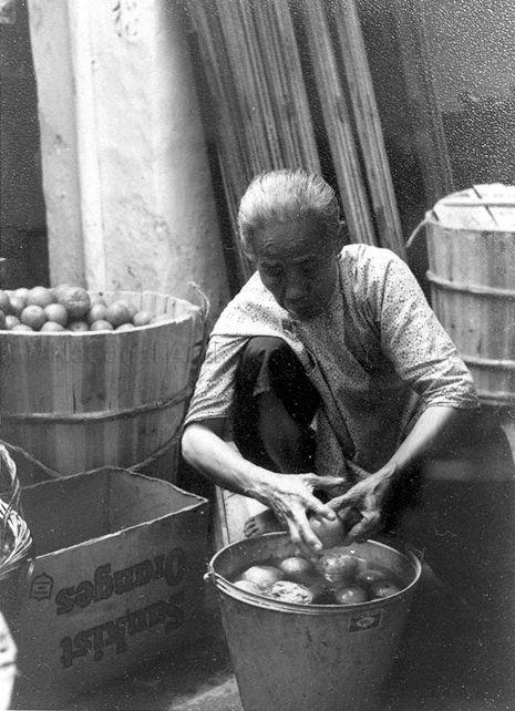 Sunkist oranges , a popular type of orange sold in Chinatown.  This old lady is washing the orange to remove the powdery elements on the skin before the fruit can be displayed.