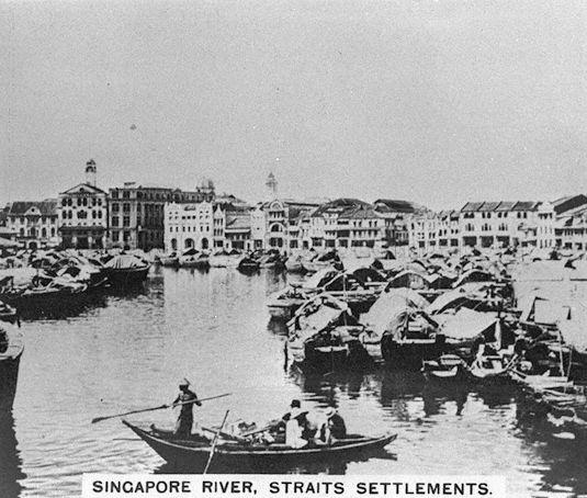 View of bumboats (also known as tongkangs in Malay) on Singapore River. Used principally to transport cargo between ships in the outer harbour and godowns along the river, they were mostly operated by Indians until 1900 when Chinese Hokkiens and Teochews took over the trade and named their bumboats "twakows" after their dialect. In the background stands the ornate Bonham Building (centre), with the dome of Chartered Bank Building at Raffles Place and the turret of Ocean Building at Collyer Quay visible.