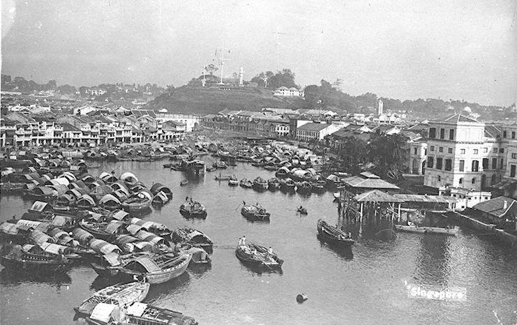Boat Quay at Singapore River, after the Fort Canning Lighthouse (background) was built. The covered landing stage on the right was the site of the original Hallpike Boatyard where boat building and repairs were carried out from 1823 to late 1860s.